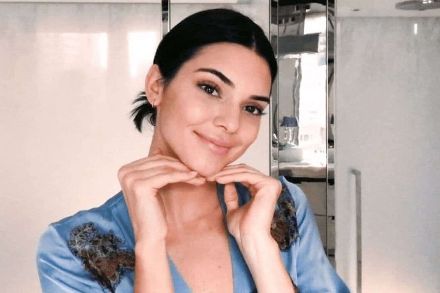 Woman demonstrating facial massage technique using knuckles on nose and cheek areas
