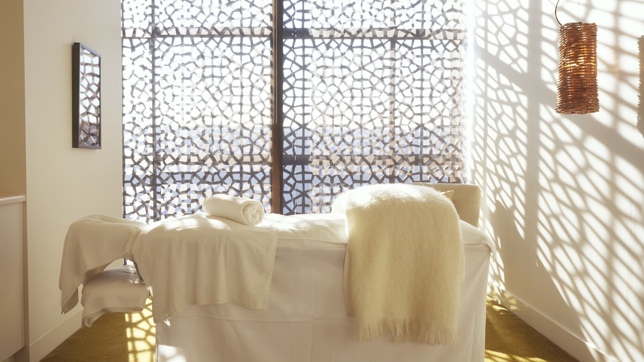 Bright, minimalist spa relaxation lounge with leather seating, wooden shutters and views over St Kilda towards Melbourne CBD