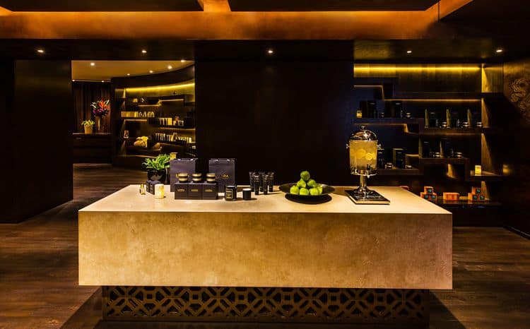 Chi Spa reception counter at Shangri-La Sydney with Sodashi skincare display, warm amber lighting and curved timber shelving
