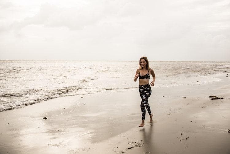 Woman doing outdoor fitness training under palm trees at tropical resort with instructor