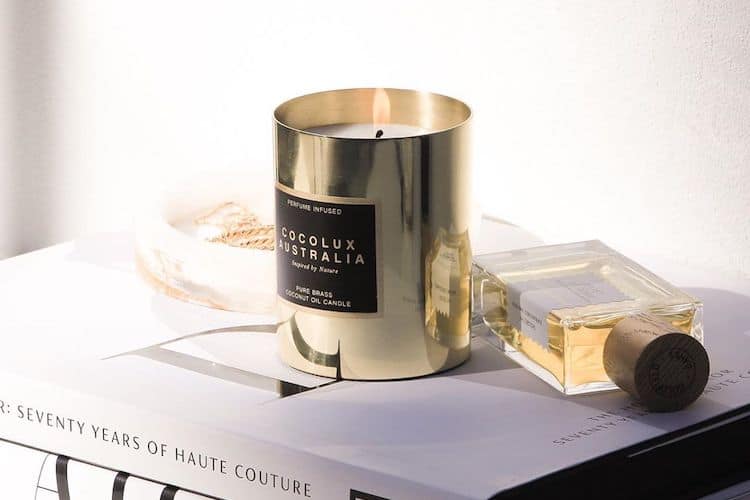 Collection of sustainable candles in glass vessels and brass holders arranged on a neutral surface