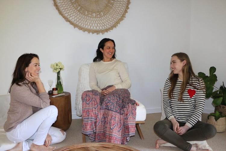 Serene meditation studio with cream walls, rattan mandala wall hanging and potted plants overlooking Sydney's Northern Beaches forest
