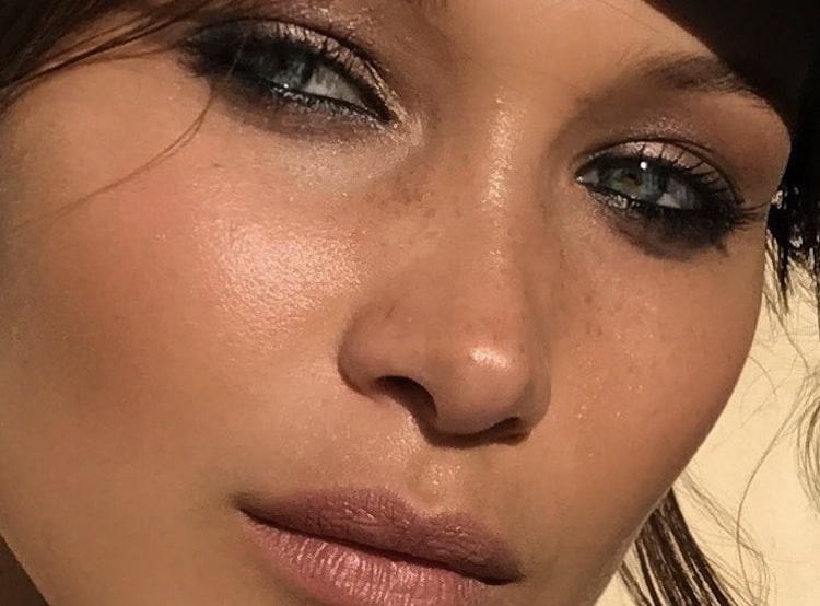 Woman with glowing, calm complexion applying skincare product to face and neck