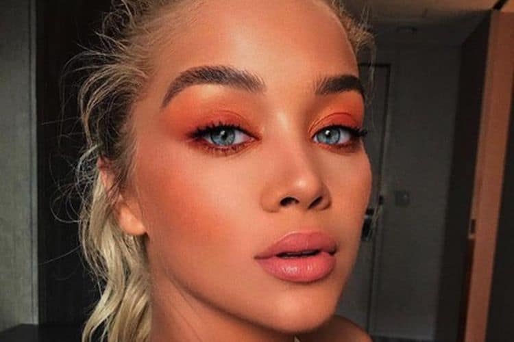 Swatches of coral beauty products including liquid lip polish, eyeshadow palette, nail polish and blush on a neutral background