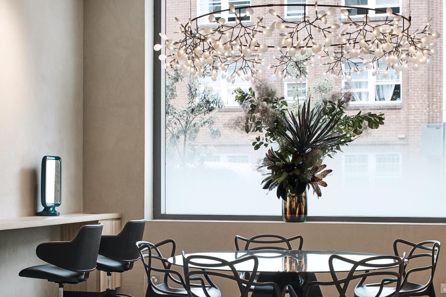 Minimalist salon interior with blue-grey onyx reception desk, pendant lighting, and asymmetrical product display windows