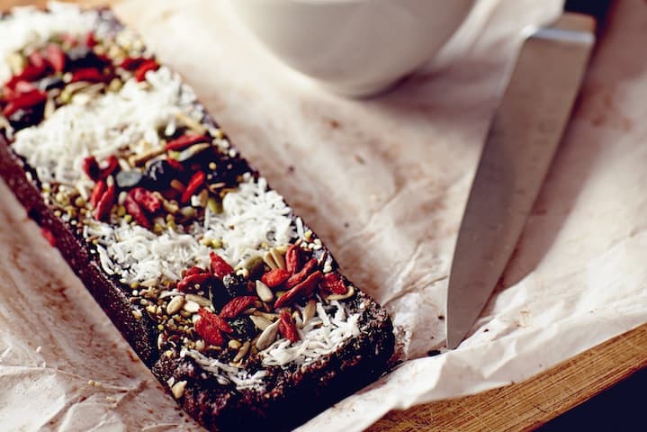 Homemade beauty brownies sliced on a plate, topped with goji berries, desiccated coconut and mixed nuts