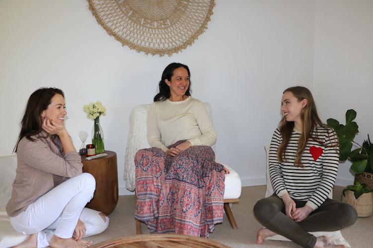 Serene meditation studio with cream walls, rattan mandala wall hanging and potted plants overlooking Sydney's Northern Beaches forest