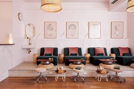 Green velvet pedicure chairs with pink cushions beneath rattan pendant lights at Polished Beauty Rooms, Byron Bay