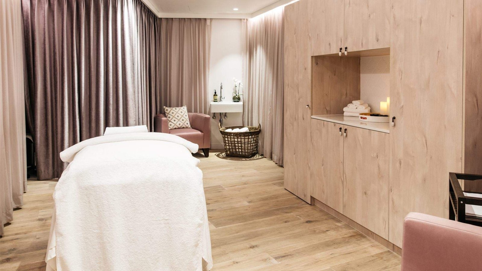 Massage bed, mauve curtains and pale timber cabinetry in a treatment room at Sol Spa, The Botanica, Vaucluse
