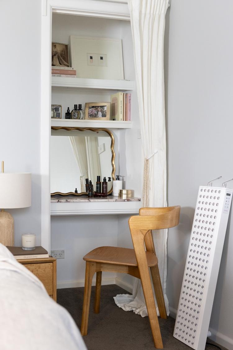 Minimalist self-care corner featuring an Infraredi red light therapy panel, wooden chair, and cozy decor in a sunlit wellness-inspired home space.
