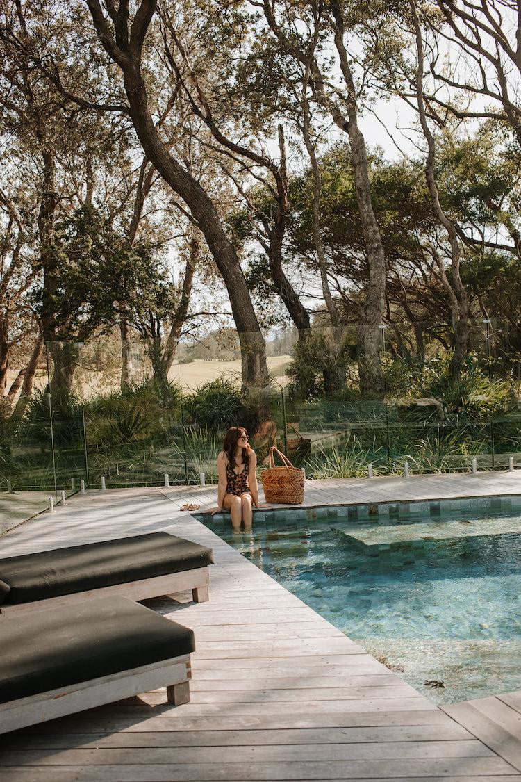 Sigourney wears Matteau swimsuit, Hermès Oran sandals, and basket from Bangalay Luxury Villas