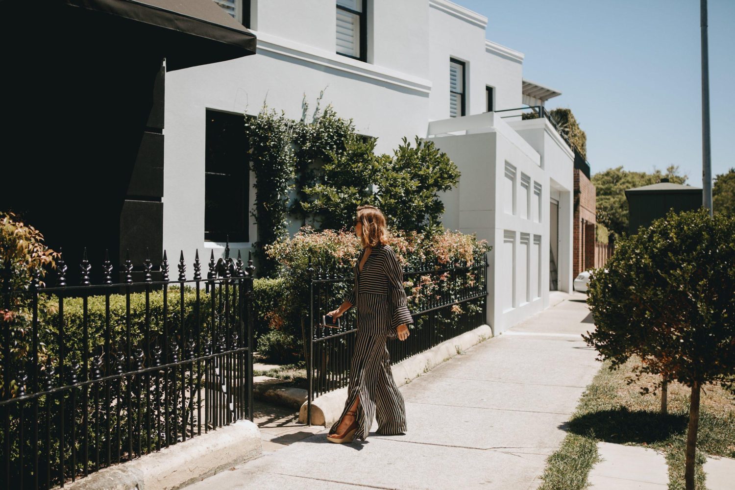 Woman in a robe standing outside All Saint Skin Clinic in natural daylight