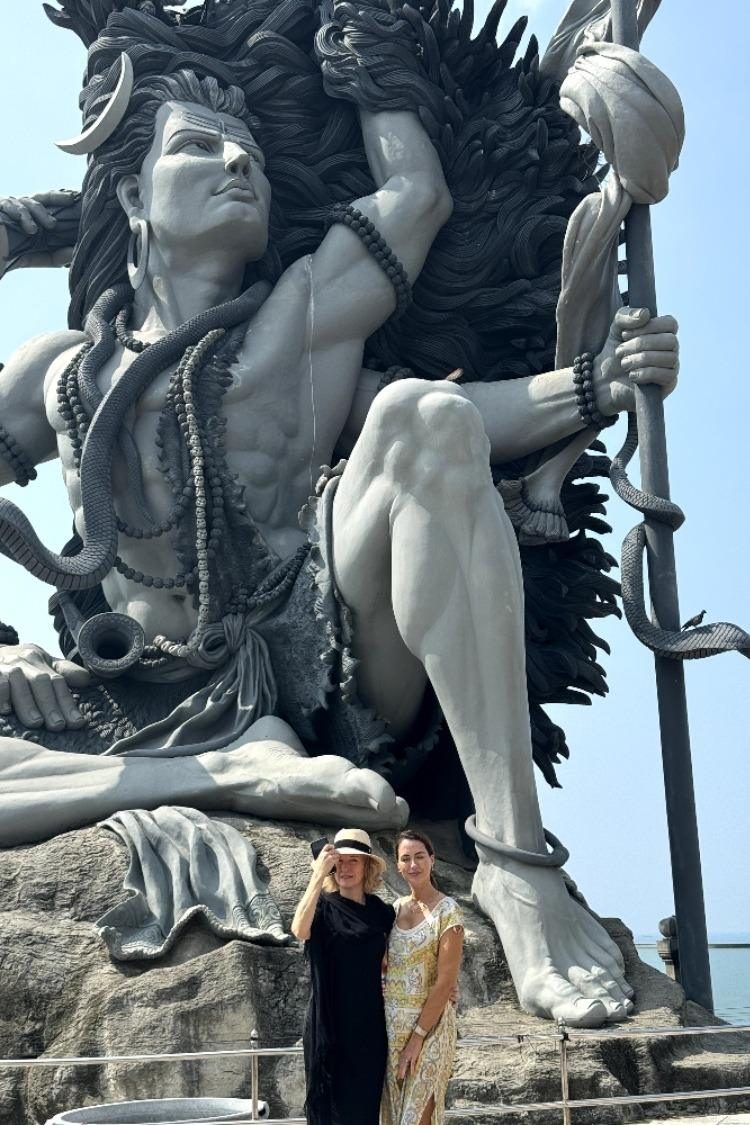 Sigourney Cantelo standing beneath a towering Shiva statue in Kerala, India