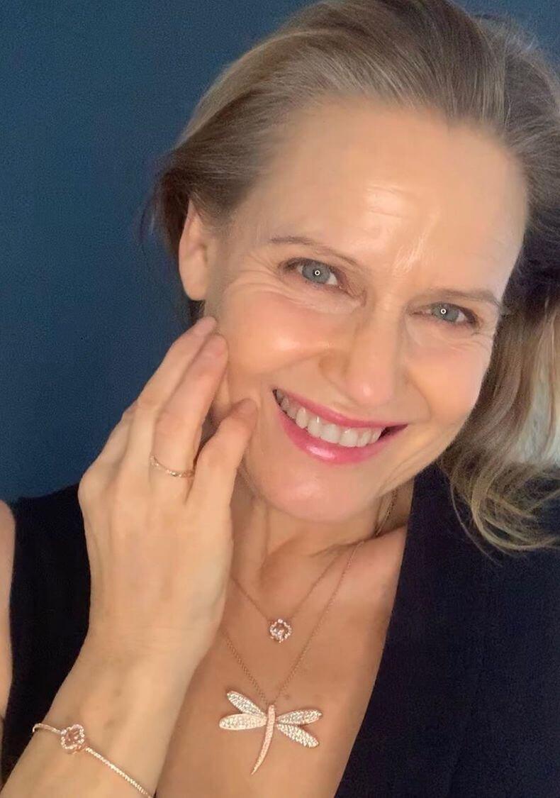 Close-up selfie of Shaynna Blaze wearing rose gold dragonfly necklace and bracelet against navy backdrop